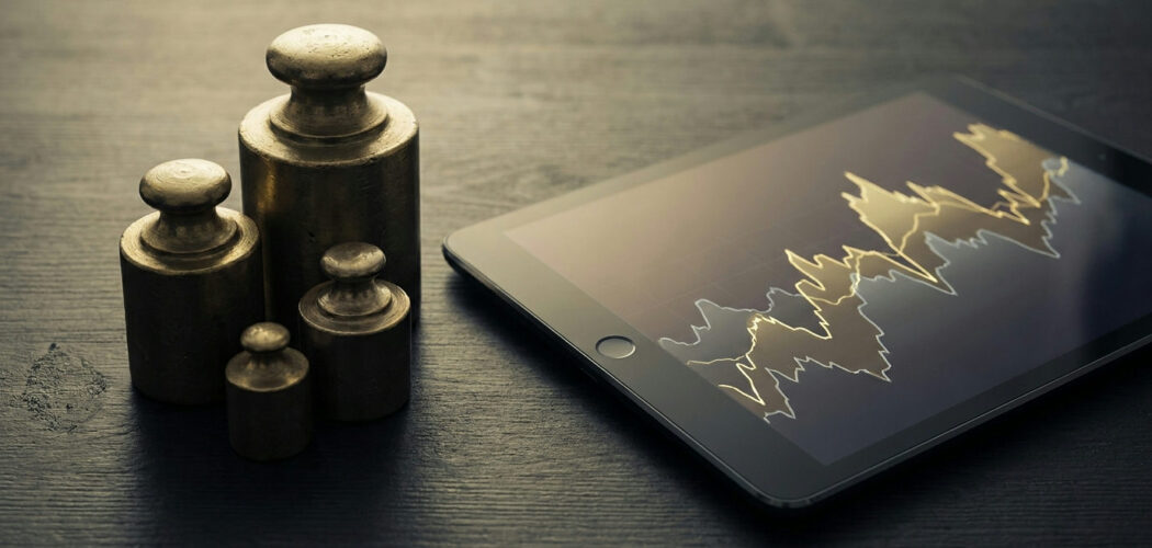 Position sizing: stacked weights of different sizes beside a tablet showing a price chart
